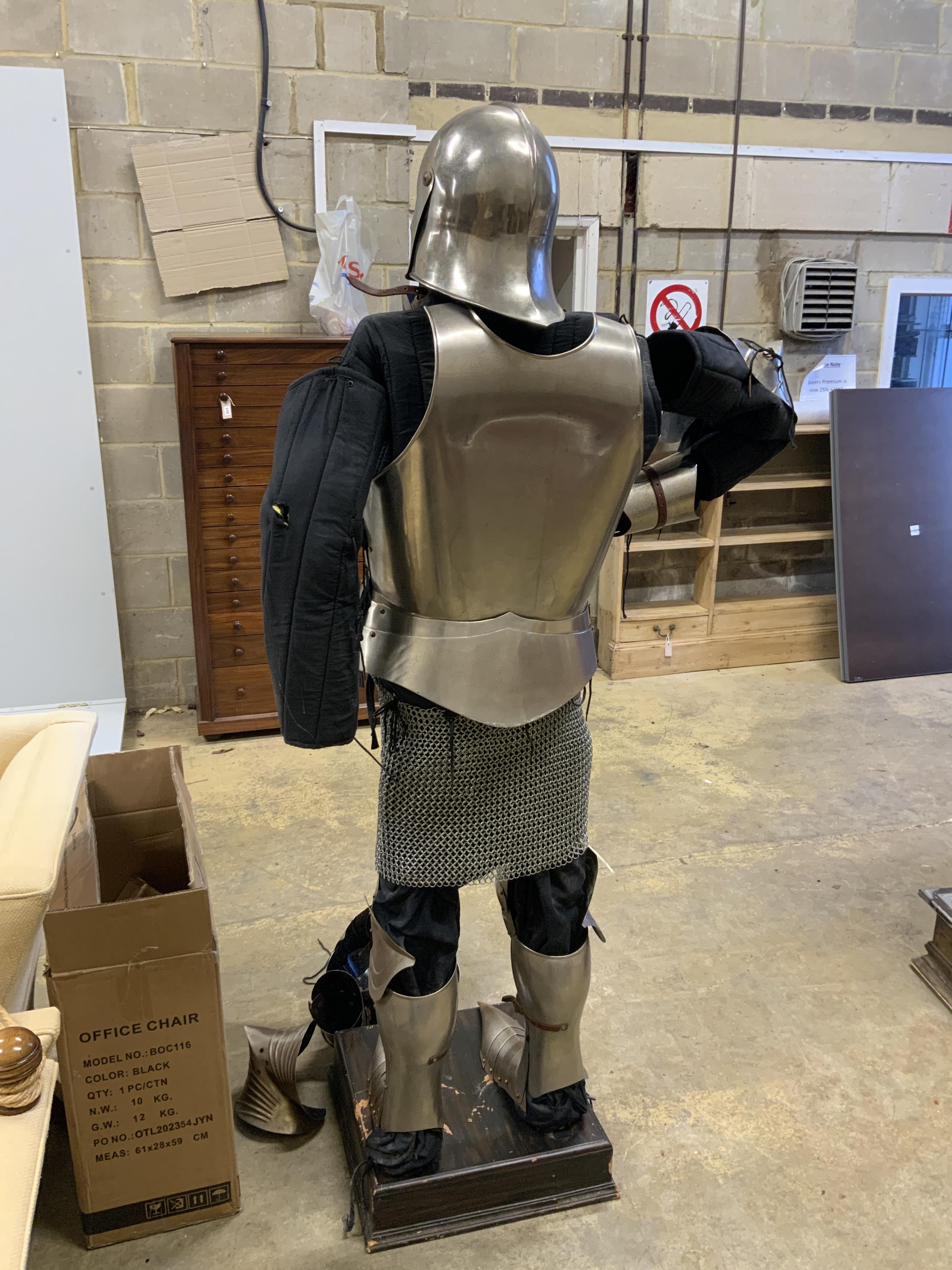 A full suit of reproduction armour on a stand, including chainmail skirt, mounted on a display stand
